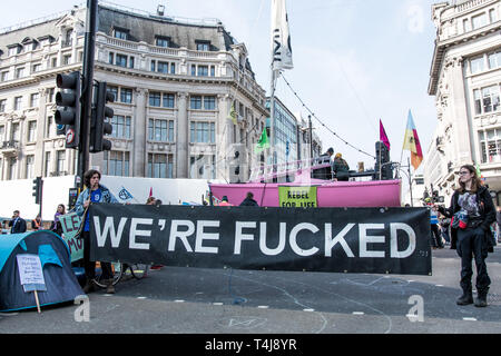 (EDITOR'S NOTE: Image enthält Weltlichkeit) Zwei Männer schneiden die Straße mit einem großen Banner in Oxford Circus mit dem Aussterben Rebellion boa im Hintergrund, während das Aussterben Rebellion Streik in London. Aussterben Rebellion Demonstranten haben fünf zentrale Wahrzeichen Londons gegen die Regierung Untätigkeit gegen den Klimawandel zu protestieren blockiert. Stockfoto