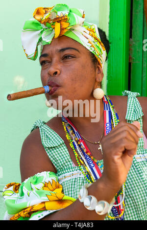 Zigarre rauchende Dame für Touristen in einer Tür weg in der Nähe des Convento de San Francisco de Asís in der Altstadt von Havanna, Kuba, Karibik posing Stockfoto