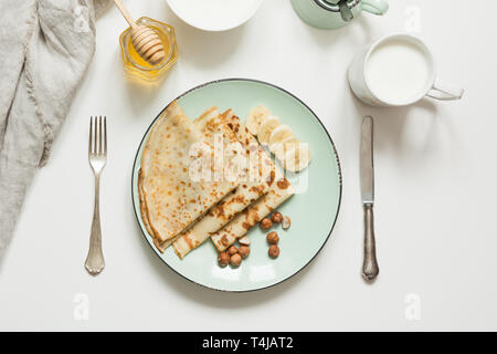 Köstliche Gerichte der traditionellen russischen Frühstück Pfannkuchen, saure Sahne, Milch, Honig an der Platte. Ansicht von oben. Traditionelle dienen. Pfannkuchen Woche. Fastnacht Stockfoto