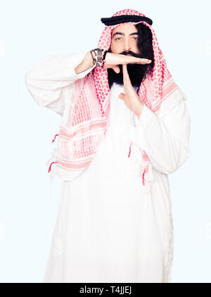 Arabian Business Mann mit langem Haar zu tragen traditionelle Kufiya Schal, Time out Geste mit den Händen, frustriert und ernstes Gesicht Stockfoto