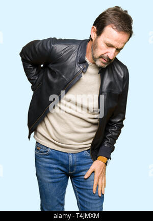 Mittleres Alter stattlicher Mann mit schwarzen Lederjacke leiden an Rückenschmerzen, Berühren mit der Hand zurück, Muskelschmerzen Stockfoto