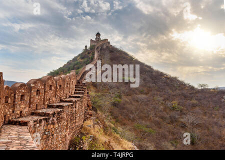 Alte lange Mauer mit Türmen um Amber Fort bei Sonnenuntergang. Jaipur. Rajasthan. Indien Stockfoto
