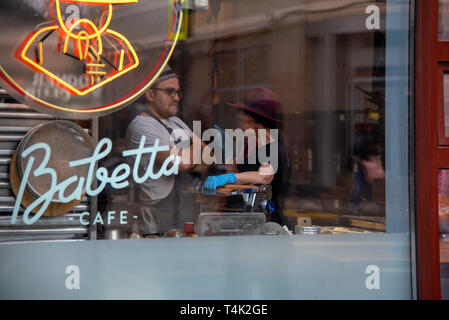 April 2019, Babett-Café Moskau, Russland. Foto gemacht durch das Café-Fenster.Das Mädchen im blauen Hut und der Handschuh, der den jungen Mann sagt, vermutlich Stockfoto