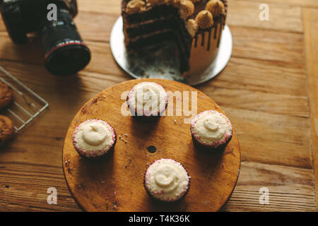 Blick von oben auf die frisch gebackenen Kuchen und einen Kuchen auf Holztisch mit einer professionellen Kamera. Dessert mit DSLR-Kamera auf den Küchentisch. Stockfoto