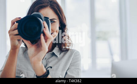 Frau Fotograf Bilder aufnehmen mit Ihrem professionelle DSLR-Kamera im Innenbereich. Weibliche unter Foto auf Digitalkamera. Stockfoto