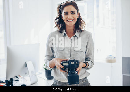 Attraktive junge Frau, die Fotografin mit Ihrer professionellen Kamera. Fotografin mit Digitalkamera im Amt. Stockfoto