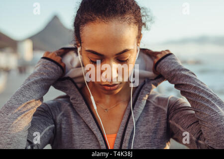 Nahaufnahme von Fitness Frau trägt ein T-Shirt und Ohrhörer im Freien. Läuferin auf im Freien Training. Stockfoto