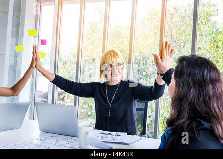 Multi-ethnischen alle glücklich und positiven Frauen mit verschiedenen Rassen High Five tun in der Mitte der Sitzung Vorstand Zimmer - Einheit und Teamarbeit Konzept Stockfoto