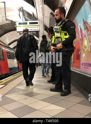 British Transport Polizisten auf Streife auf der Central Line Plattform der U-Bahnhof Bank als zwei Aussterben Rebellion Demonstranten an Bord die Beförderung eines Docklands Light Railway (DLR) an der Station Canary Wharf im Osten Londons erklommen und sagen Sie selbst Klebstoff auf dem Dach, im Rahmen der laufenden Klimawandel Proteste in der Hauptstadt. Stockfoto