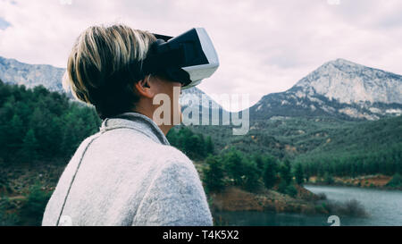 Frau in der Natur tragen augmented reality goggles. Erwachsene weiblich Spaß mit AR Brille auf. Fliegen. Spielen. Tagsüber. Stockfoto