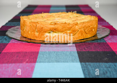 Gesichert knackig und süße hausgemachte Cherry Pie auf einer Glasplatte und einem Tisch mit bunten Würfel Muster Tuch bedeckt in der Nähe Stockfoto