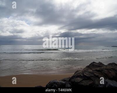 Vom Strand in Coffs Harbour, Australien, mit Blick über den silbernen Pazifik bis zur Horizont-Linie, kaum erkennbar an den grauen Wolken Stockfoto