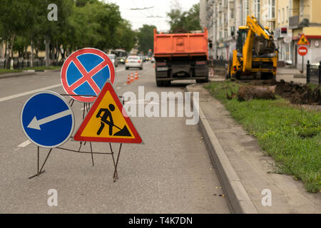 Verkehrszeichen, Umweg, Straße Reparatur auf der Straße Hintergrund, Lkw und Bagger gräbt Loch Stockfoto