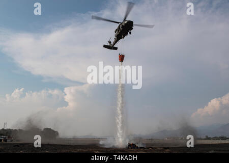 Ein UH-60 Blackhawk vom 1-228 th Aviation Regiment zielt darauf ab, eine simulierte wildfire zu löschen, die zusätzlichen Möglichkeiten der Gemeinsamen Task Force - Bravo während der Mittelamerika Austausch von gegenseitigen operationeller Kenntnisse und Erfahrungen (CENTAM RAUCH) Übung, 11. April 2019 zu zeigen, im Soto Cano Air Base, Honduras. CENTAM RAUCH brachte Feuerwehrmänner aus Honduras, Costa Rica, Belize, Guatemala und El Salvador mit US Air Force Mitglieder zu trainieren sowie Anleihen und Verständnis der jeweils anderen Kultur mit team building Übungen entwickeln. Die einwöchige Schulung Flugzeuge und Struc Stockfoto