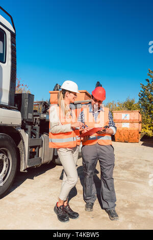 Arbeitnehmer Unterzeichnung Papiere zu Abriss Bauschutt Container geliefert Stockfoto