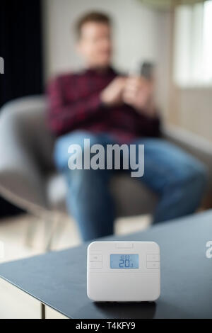 Man Controlling Zentralheizung Smart Meter über App auf dem Mobiltelefon Stockfoto