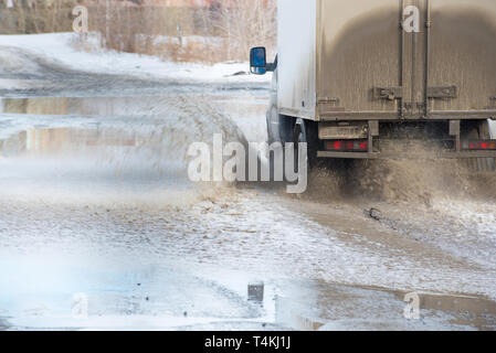 Schmutzige Welle von Spray unter die Räder eines Fahrzeugs. Wasser auf der Straße. Stockfoto