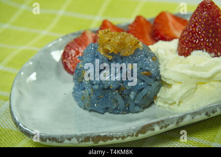 Blauen Erbse klebriger Reis Hackfleisch Fisch mit Kokosmilch mit Erdbeeren und Sahne serviert, thailändisches Dessert Asian Food Styling. Stockfoto