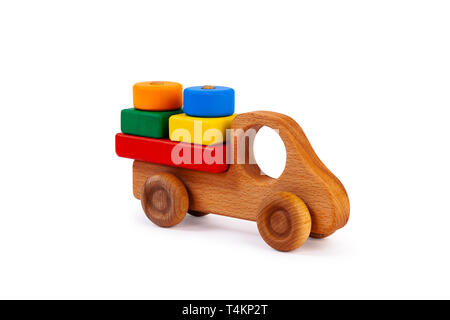 Foto von einem hölzernen Auto Lkw beladen mit kleinen bunten geometrischen Figuren aus Holz: ein Kreis, ein Dreieck, ein Rechteck, ein Quadrat aus Buche auf einem weißen Stockfoto