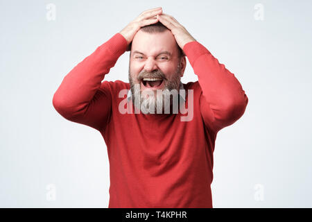 Schöne reife bärtiger Mann im roten Pullover Lachen auf seinem Freund Witz. Studio shot Stockfoto