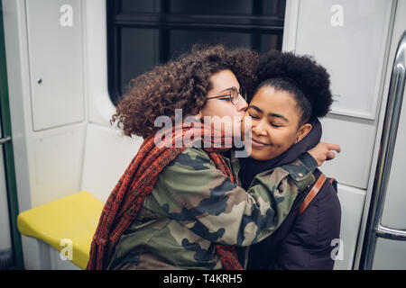 Zwei Freunde, die in der U-Bahn küssen und umarmen - Reisen, Metropolitan, fröhlichen Stockfoto