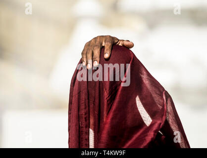 Eine junge novizin Mönch betet unter seinem roten Roben vor der Shwedagon Pagode, Myanmar. Stockfoto