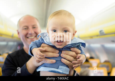 Vater steht mit seinen sechs Monate alten Baby im Flugzeug Stockfoto