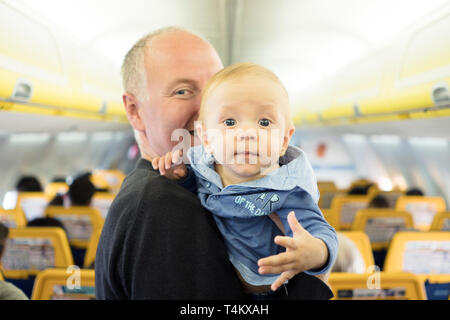 Vater steht mit seinen sechs Monate alten Baby im Flugzeug Stockfoto