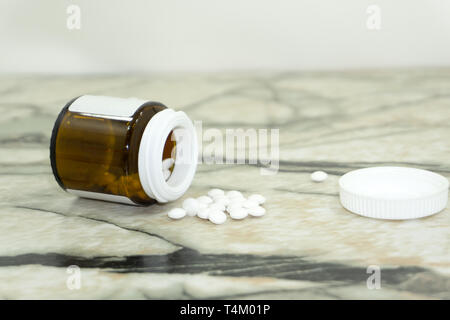 Weiße Pillen aus braunem Glas Glas auf einem hellen gelben Hintergrund bröckeln Stockfoto
