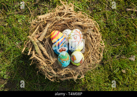 Detail bemalte Ostereier mit verschiedenen Formen, Cartoons und helle Farben in einem Vogelnest im Freien an einem sonnigen Tag Stockfoto