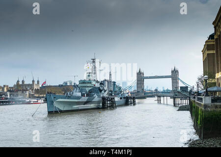 Die touristische Attraktion der HMS Belfast günstig auf der Themse in London mit dem Tower of London und die Tower Bridge im Hintergrund. Stockfoto