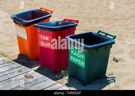 Drei Abfallbehälter aus Kunststoff für getrennte Müll auf einem Sandstrand. Stockfoto