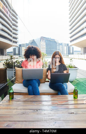 Zwei junge Frauen, die als Praktikanten oder Studenten gemeinsam auf dem Laptop Lernen Stockfoto