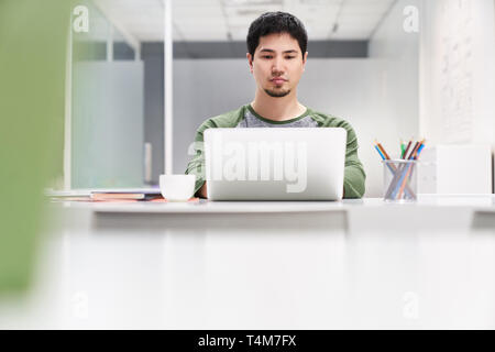 Junger Mann als Programmierer oder Softwareentwickler bei Laptop Stockfoto