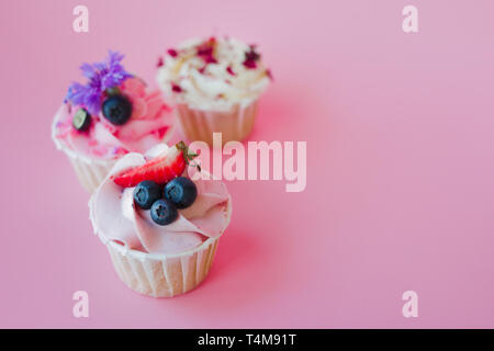 Der leckere Cupcakes mit verschiedenen Füllungen und Creme. Die drei Muffin mit Sahne auf einem rosa Hintergrund, kopieren. Stockfoto