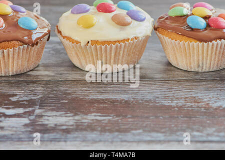 Muffins, beschichtet mit Schokolade in einer Reihe, Holz- Hintergrund mit Kopie Raum Stockfoto