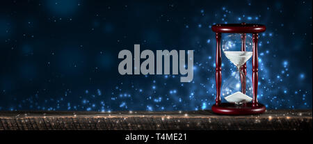 Vintage Sanduhr am Holztisch mit funkelnden blauen Bokeh Hintergrund-Konzept Stockfoto