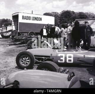 1960 s, historischen Motorsport Rennstrecke im Crystal Palace in London, London, England, UK. Autos auf dem Gras von Lkw geparkt, durch Radio London gefördert. Stockfoto