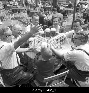 Jubel auf die Ankündigung, dass München die Olympischen Sommerspiele 1972 werden in einem Biergarten in München (Bayern, Deutschland) am 27. April 1966. | Verwendung weltweit Stockfoto