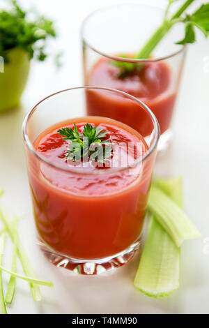 Tomatensaft in ein Glas mit Blätter der Petersilie und Sellerie. Stockfoto