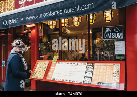 London, Großbritannien - 13 April, 2019: die Menschen und Lesen ein Menü vor einem Restaurant in Chinatown, London. Chinatown ist die Heimat einer großen Ostasiatischen kom Stockfoto