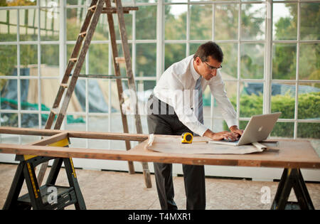 Geschäftsmann Texteingabe auf einem Laptop auf einer Baustelle. Stockfoto