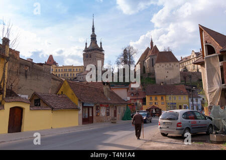 Alba Iulia, Rumänien - 9. April 2019: Alter Mann mit einem Stock zu Fuß auf der Straße in Sighisoara unter bunten Häusern und alten Läden. Stockfoto