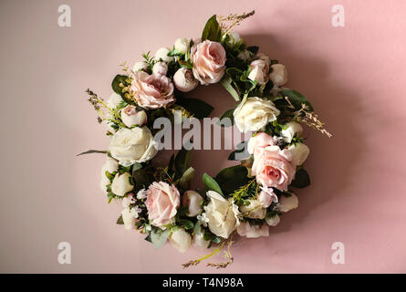 Kranz von rosa und weißen Rosen, grüne Blätter, Zusammensetzung rosa Blumen und grüne Blätter formen kreisförmige Rahmen auf rosa Hintergrund, Flach, Overhead Stockfoto