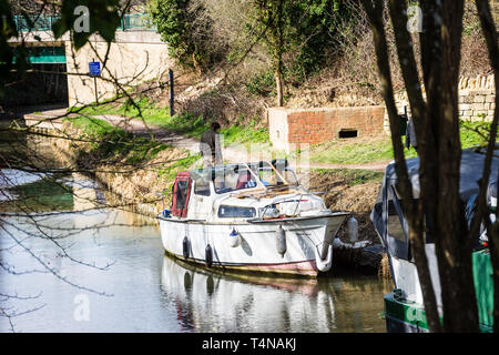 Ein Mann stand hinter einem kleinen alt und abgenutzt river Cruiser Boat auf der Kennet und Avon Kanal vor der alten Welt Krieg 2 Pille box günstig. Stockfoto