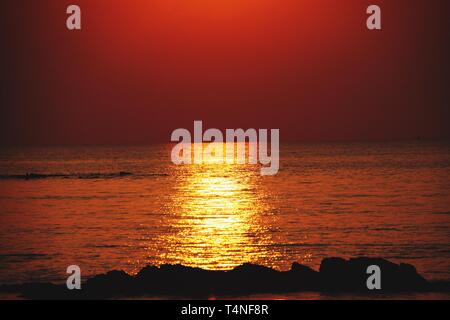 Sunbeam bei Sonnenuntergang casting lange gelbe Helle golden schimmernden Lichtstrahl über den Ozean. Ko Lanta, Thailand Stockfoto