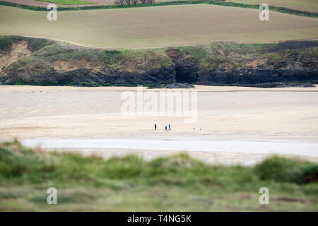 Die fernen Figuren der Hund Spaziergänger auf Crantock Strand bei Ebbe in Newquay in Cornwall. Stockfoto