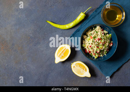 Tabbouleh Salat mit Couscous, Petersilie, Zitrone, Tomaten, Olivenöl. Levantinischen vegetarischen Salat. Libanesische und arabische Küche. Der dunkle Hintergrund. Ansicht von oben. Spa Stockfoto
