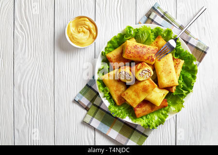 Herzhaften crepe Brötchen mit Hähnchen Fleisch und Pilzen füllen serviert auf einem schlechten frische Salatblätter auf einem weißen Teller auf einem Holztisch mit Chee Stockfoto