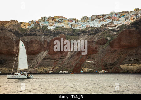 Anzeigen von Fira und einem Katamaran aus dem Meer in der Nähe von Santorini Stockfoto